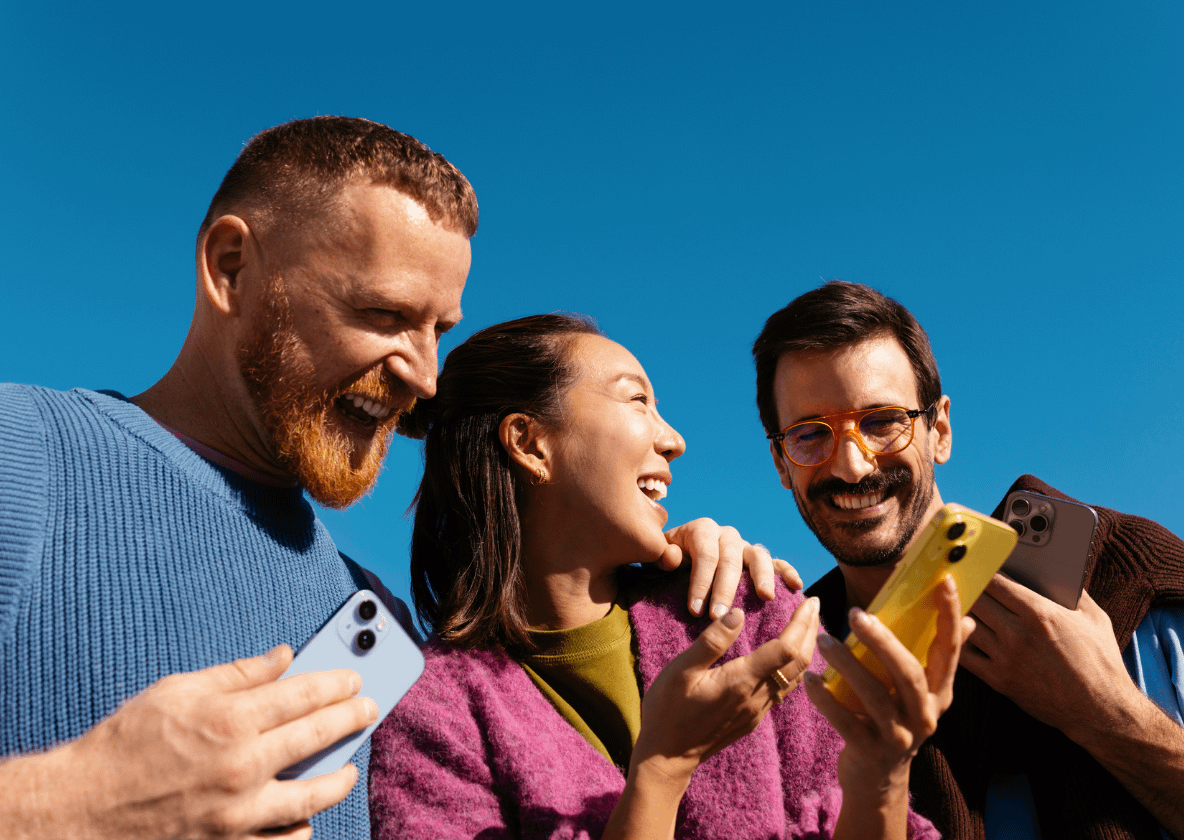 Drei Menschen lachen gemeinsam über ihre Smartphones